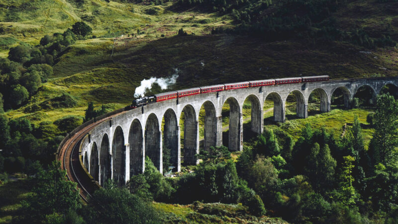 Luxury steam train travelling through vibrant green mountains, exemplifying how La Fugue offers bespoke journeys that provide a unique narrative of cultural experiences, art, heritage, and exclusive luxury, personalised to your tastes in luxury travel