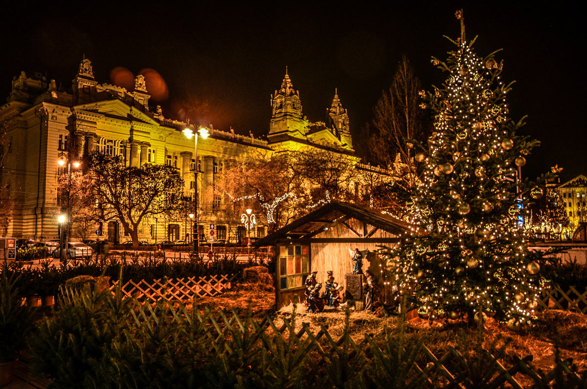 A stunning night view of the Advent Feast at the Basilica in Budapest, Hungary, featuring a beautifully lit Christmas tree and a detailed nativity scene display, perfect for luxury Christmas travel to European Christmas markets.