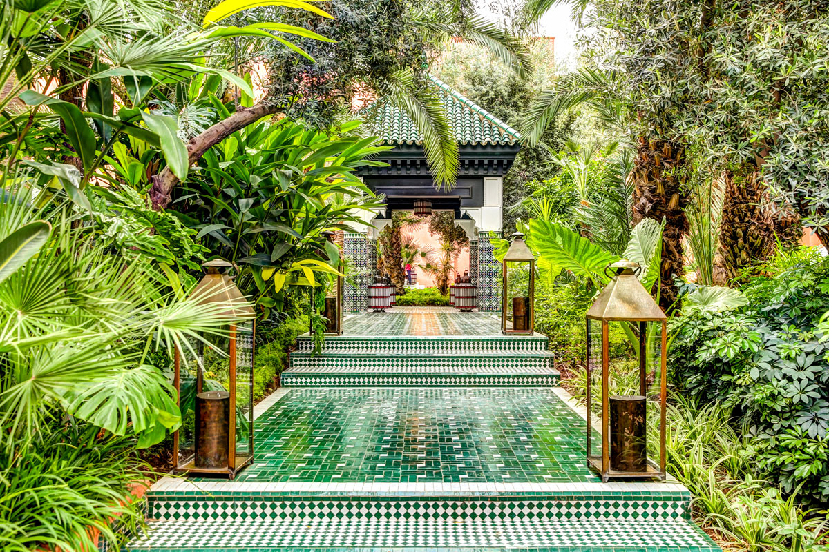 Tile-patterned paths wind through lush green gardens in Marrakech, Morocco, offering a serene escape perfect for luxury travel and private jet winter getaways.